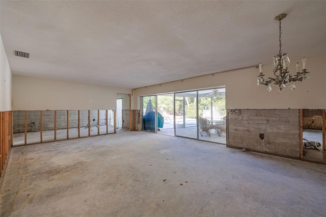 empty room featuring a notable chandelier and a textured ceiling