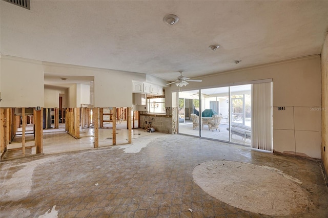 unfurnished living room with a textured ceiling, ceiling fan, and crown molding