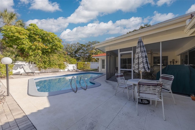 view of swimming pool featuring a grill, a patio area, and a sunroom