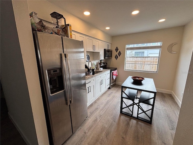 kitchen with hardwood / wood-style floors, sink, white cabinetry, and stainless steel appliances