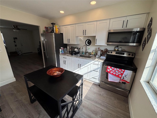 kitchen featuring sink, ceiling fan, light stone countertops, white cabinetry, and stainless steel appliances