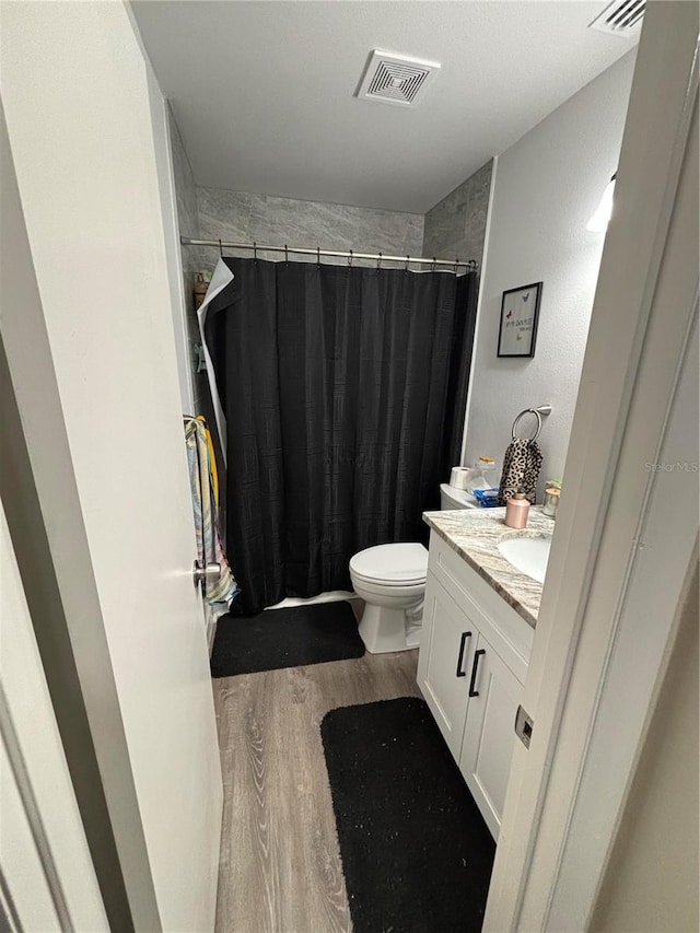 bathroom featuring hardwood / wood-style floors, vanity, toilet, and curtained shower