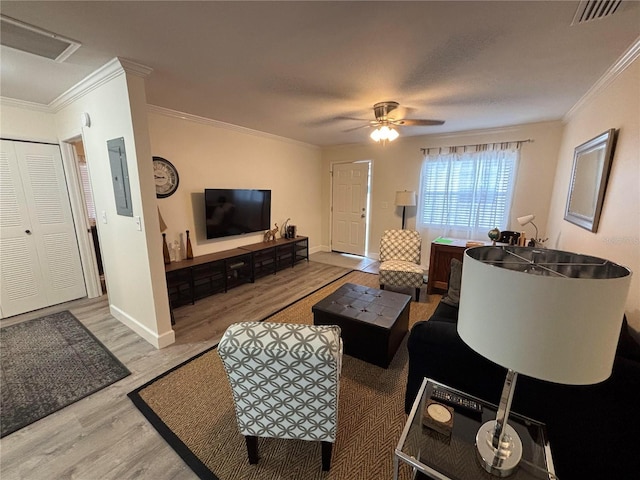 living room with electric panel, ceiling fan, ornamental molding, and light wood-type flooring