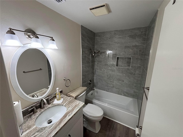 full bathroom with hardwood / wood-style floors, tiled shower / bath combo, toilet, and vanity