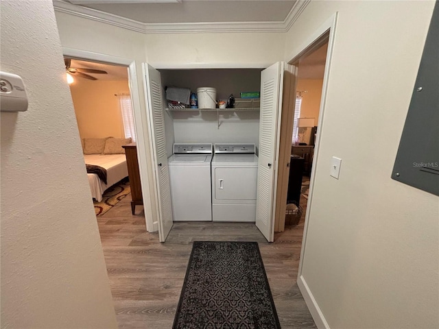 clothes washing area with washing machine and dryer, ceiling fan, wood-type flooring, and ornamental molding