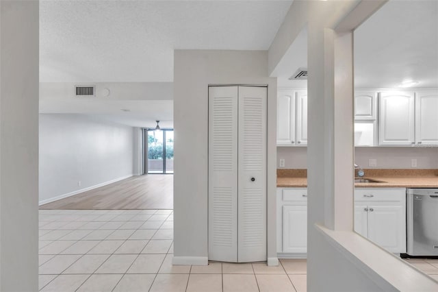 kitchen featuring dishwasher, sink, white cabinets, and light tile patterned flooring