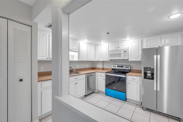 kitchen featuring white cabinetry, sink, light tile patterned floors, and appliances with stainless steel finishes