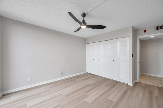 unfurnished bedroom with a textured ceiling, a closet, ceiling fan, and light hardwood / wood-style floors