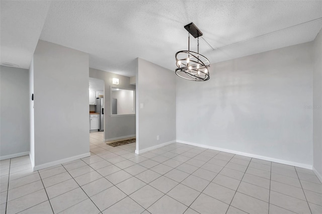 empty room with light tile patterned floors, a textured ceiling, and an inviting chandelier