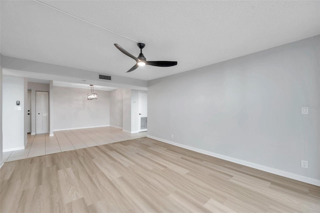 unfurnished living room with ceiling fan, light hardwood / wood-style floors, and a textured ceiling