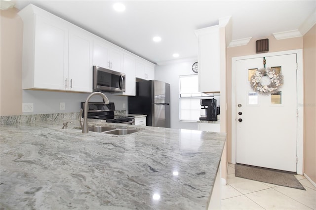 kitchen featuring appliances with stainless steel finishes, white cabinets, ornamental molding, light tile patterned floors, and light stone countertops