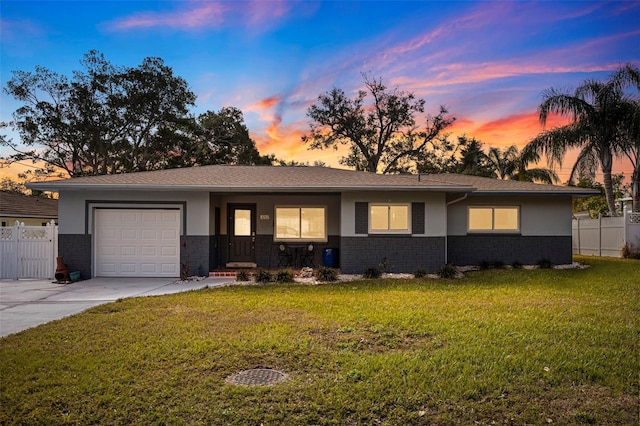 single story home featuring a garage and a lawn