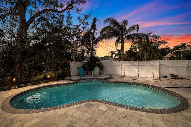 pool at dusk featuring a patio