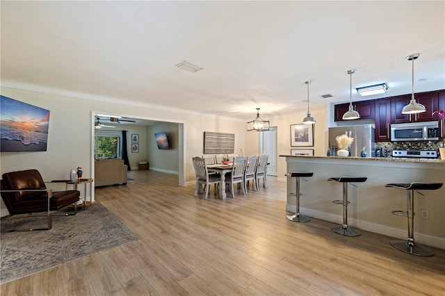 interior space featuring ceiling fan with notable chandelier and light hardwood / wood-style flooring