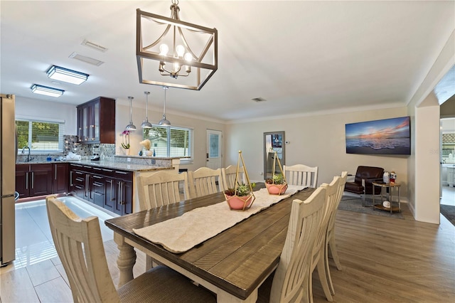 dining area with a healthy amount of sunlight, sink, a chandelier, and light hardwood / wood-style flooring