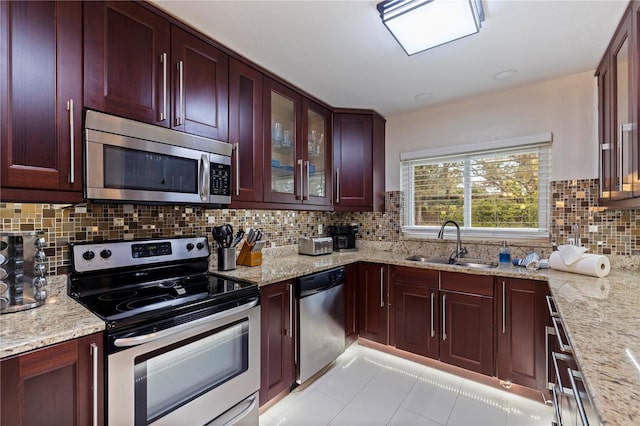 kitchen with light stone countertops, stainless steel appliances, decorative backsplash, sink, and light tile patterned flooring