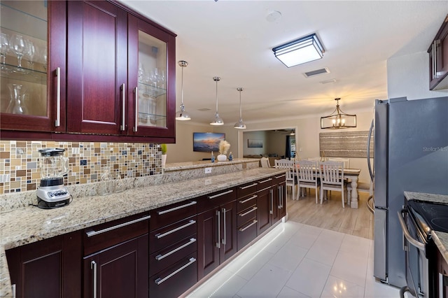 kitchen with decorative backsplash, light stone countertops, hanging light fixtures, and appliances with stainless steel finishes