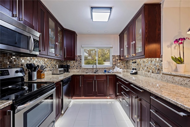 kitchen with light stone countertops, stainless steel appliances, backsplash, and sink