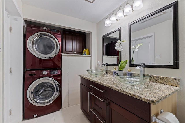 clothes washing area featuring sink, stacked washer / drying machine, and light tile patterned flooring