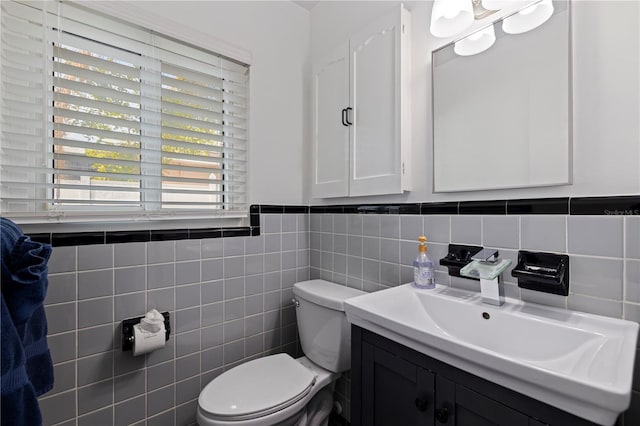 bathroom featuring toilet, vanity, and tile walls