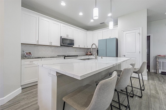 kitchen featuring a center island with sink, light hardwood / wood-style floors, white cabinets, and appliances with stainless steel finishes