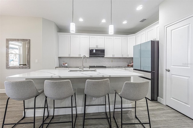 kitchen featuring sink, white cabinets, stainless steel appliances, and light hardwood / wood-style flooring