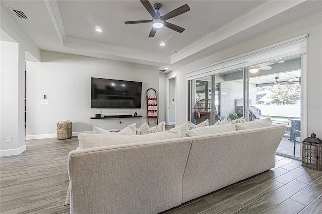 living room featuring ceiling fan, crown molding, and a tray ceiling