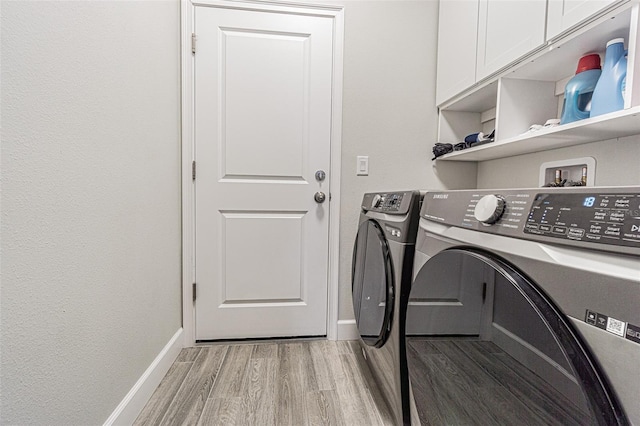 laundry area with cabinets, light hardwood / wood-style floors, and washer and clothes dryer