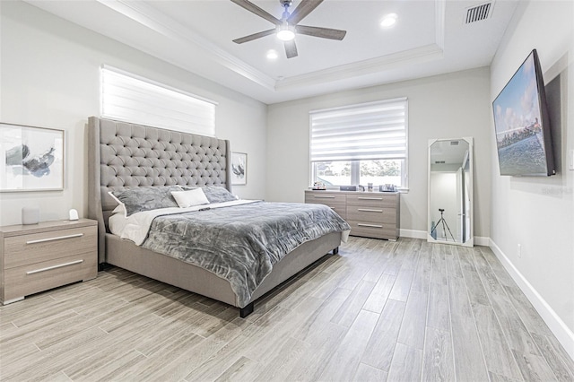 bedroom featuring ceiling fan, light hardwood / wood-style floors, and a tray ceiling