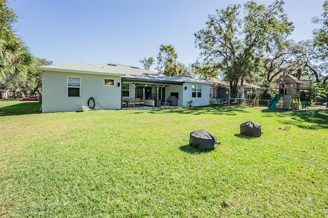 back of property featuring a playground, a trampoline, and a yard