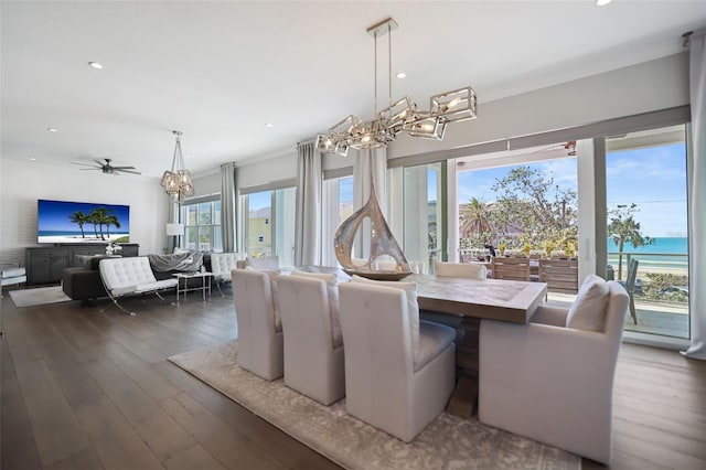 dining room featuring recessed lighting, ceiling fan with notable chandelier, a water view, and wood-type flooring