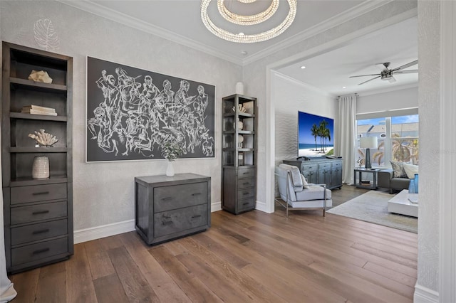 living area with built in shelves, crown molding, baseboards, wood finished floors, and a ceiling fan