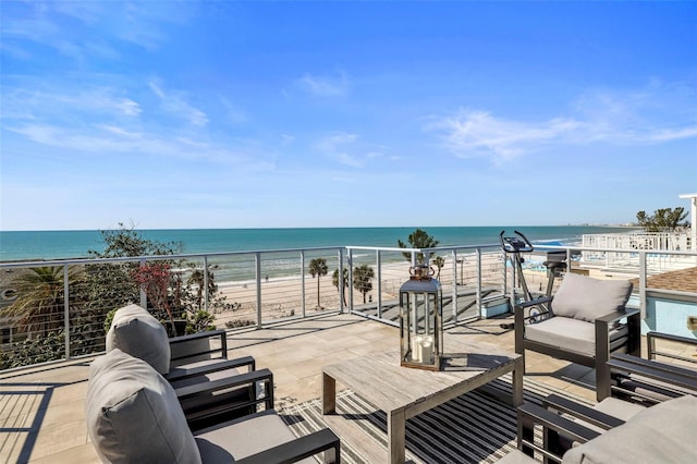 view of patio with an outdoor living space, a water view, and a view of the beach