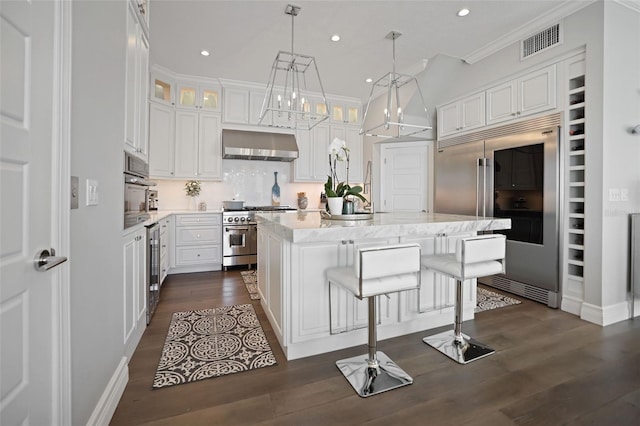 kitchen with visible vents, dark wood finished floors, white cabinets, wall chimney range hood, and premium appliances