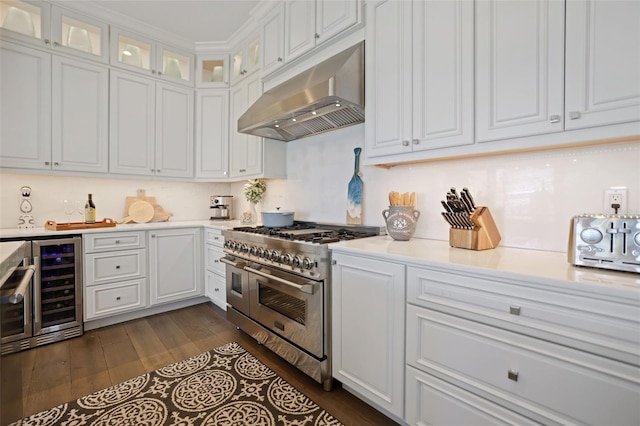 kitchen with under cabinet range hood, beverage cooler, white cabinetry, and double oven range