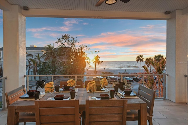 balcony featuring a water view, outdoor dining space, and a ceiling fan