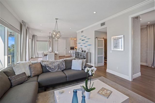 living area with wood finished floors, visible vents, baseboards, crown molding, and a barn door