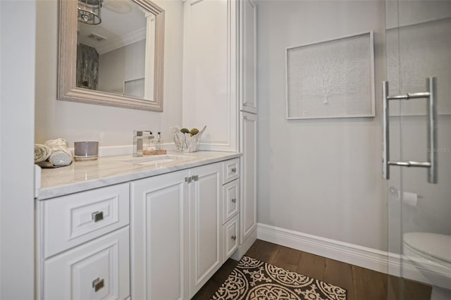 full bathroom featuring a shower with door, baseboards, toilet, wood finished floors, and vanity