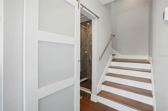 stairs with a barn door and wood finished floors