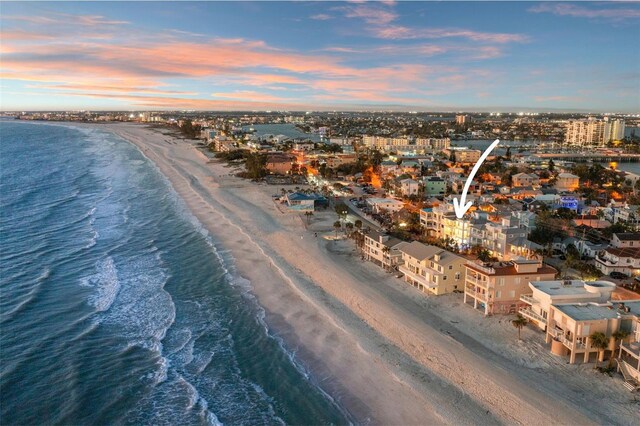 aerial view at dusk featuring a view of the beach, a view of city, and a water view