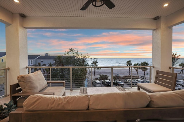 balcony at dusk featuring an outdoor living space, a water view, and ceiling fan