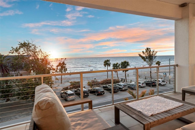 balcony at dusk featuring a water view