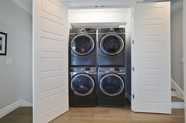 laundry room with laundry area, wood finished floors, baseboards, and stacked washing maching and dryer