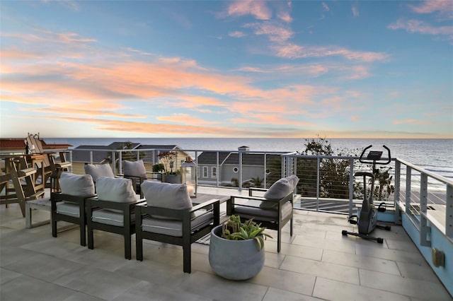 patio terrace at dusk featuring outdoor lounge area and a water view