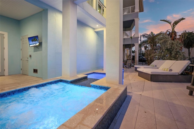 pool at dusk featuring a patio area and an outdoor pool