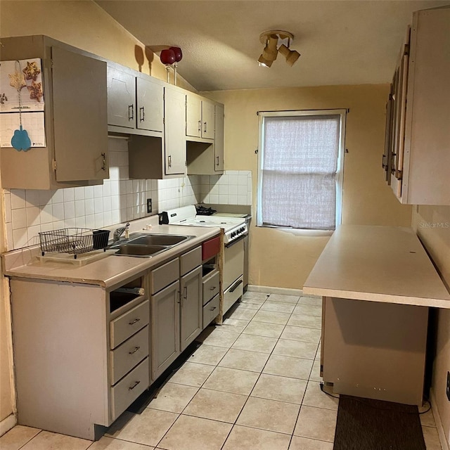 kitchen with lofted ceiling, backsplash, electric stove, sink, and light tile patterned floors