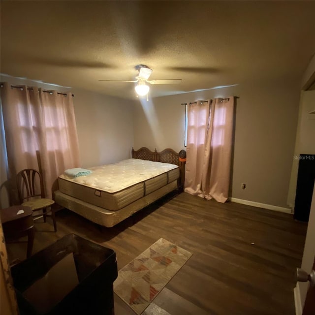 bedroom with dark hardwood / wood-style floors, ceiling fan, and a textured ceiling