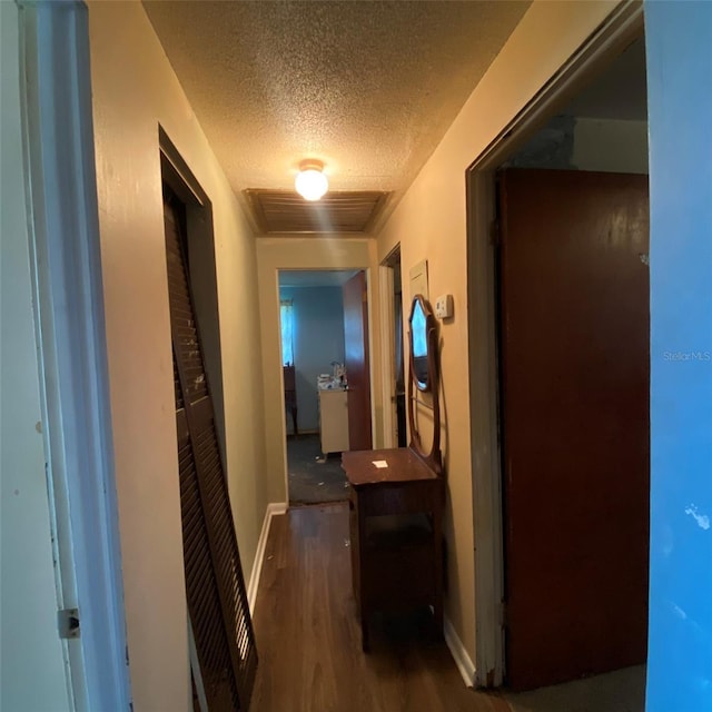 corridor with a textured ceiling and dark wood-type flooring