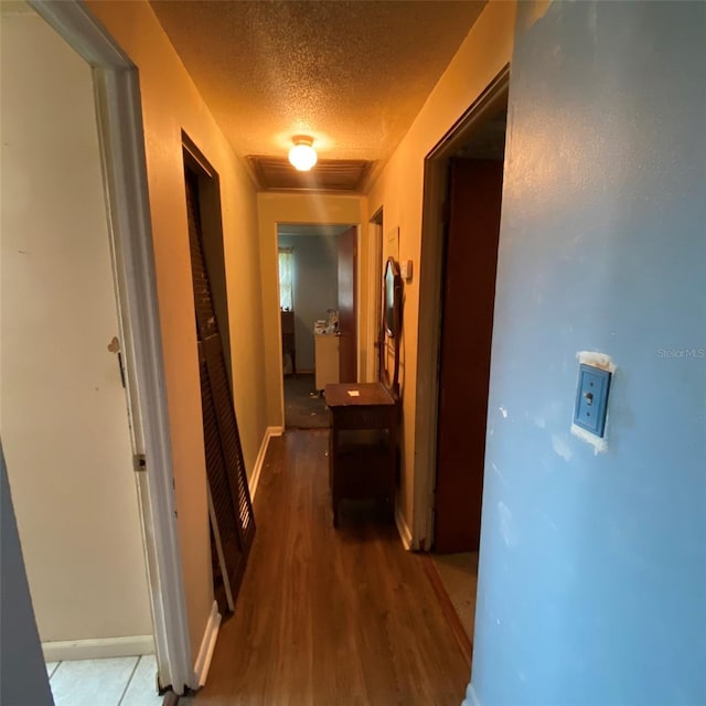 corridor featuring a textured ceiling and dark wood-type flooring