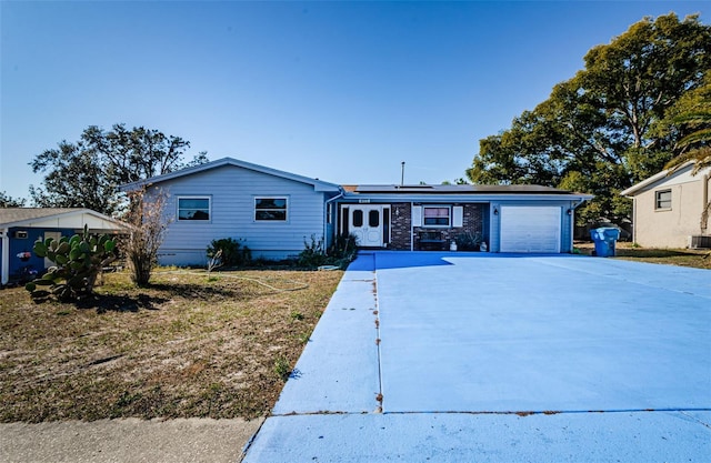 single story home with central air condition unit, a garage, and solar panels